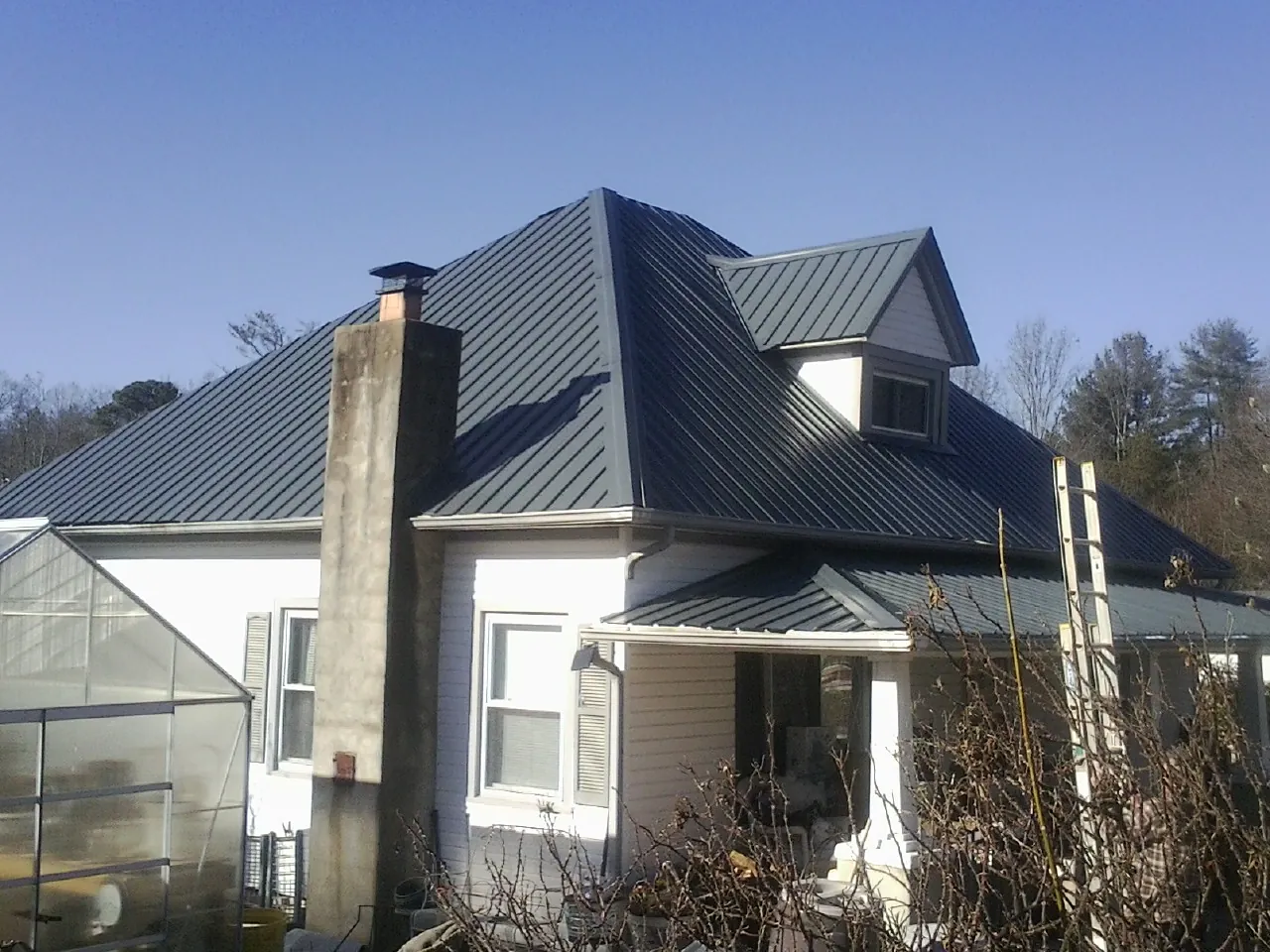 Dark blue standing seam metal roof on a white farmhouse with dormer — Slate & Tile Roof Repair by Roofing Brothers in Mashantucket