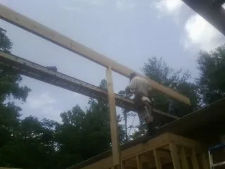 Carpenter setting a ridge beam over a new addition frame — Ice Dam Removal by Roofing Brothers in Mashantucket