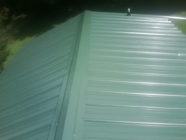 New green metal panels meeting at the ridge of a roof — Flat Roof Repair work by our crew in Mashantucket